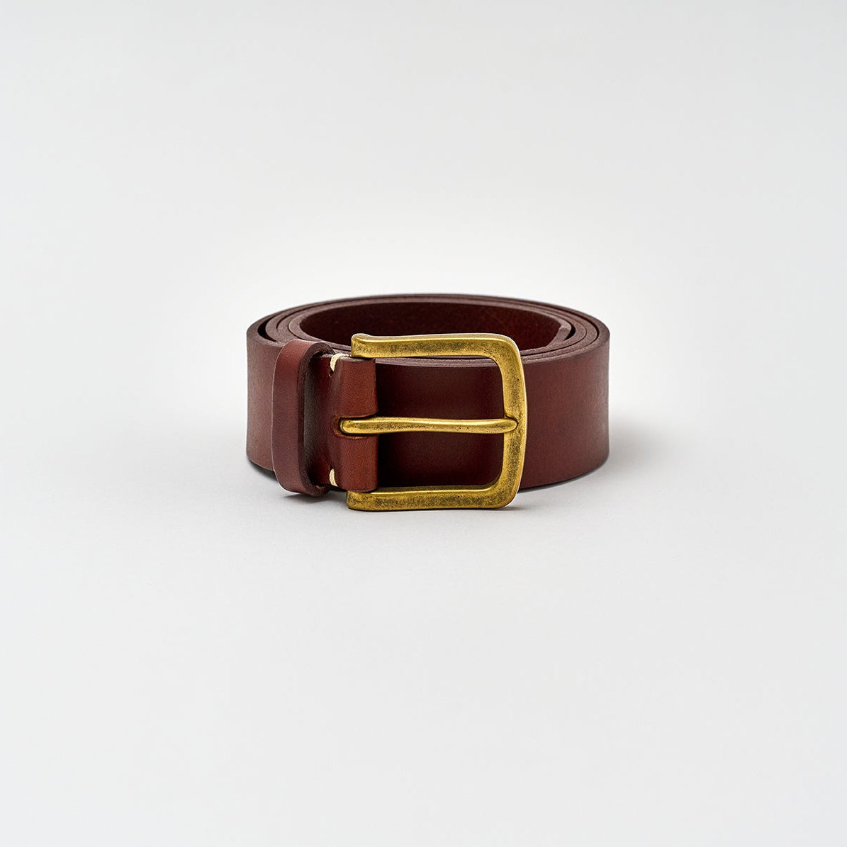 Brown leather belt with a gold buckle on a light gray background
