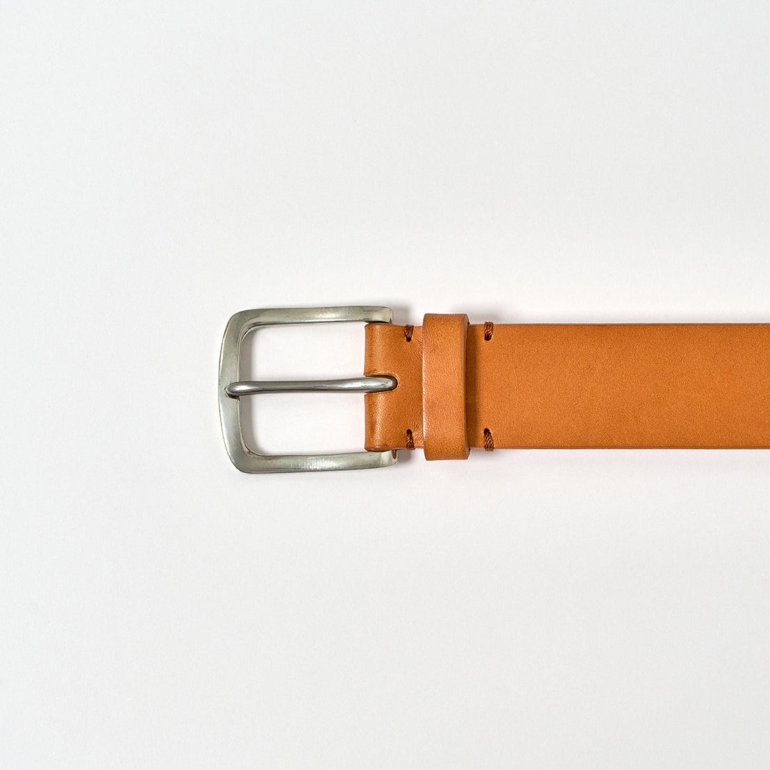 Brown leather belt with a silver buckle on a light gray background