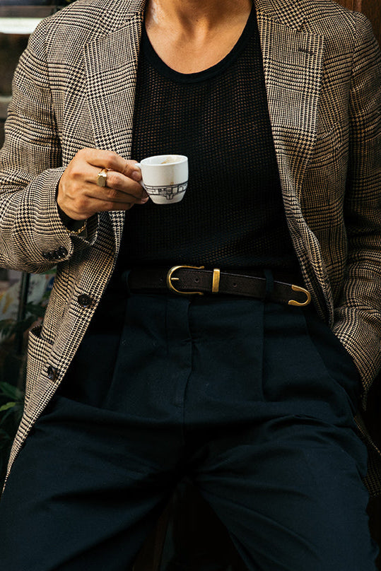 Person holding a small cup with a plaid jacket and black outfit