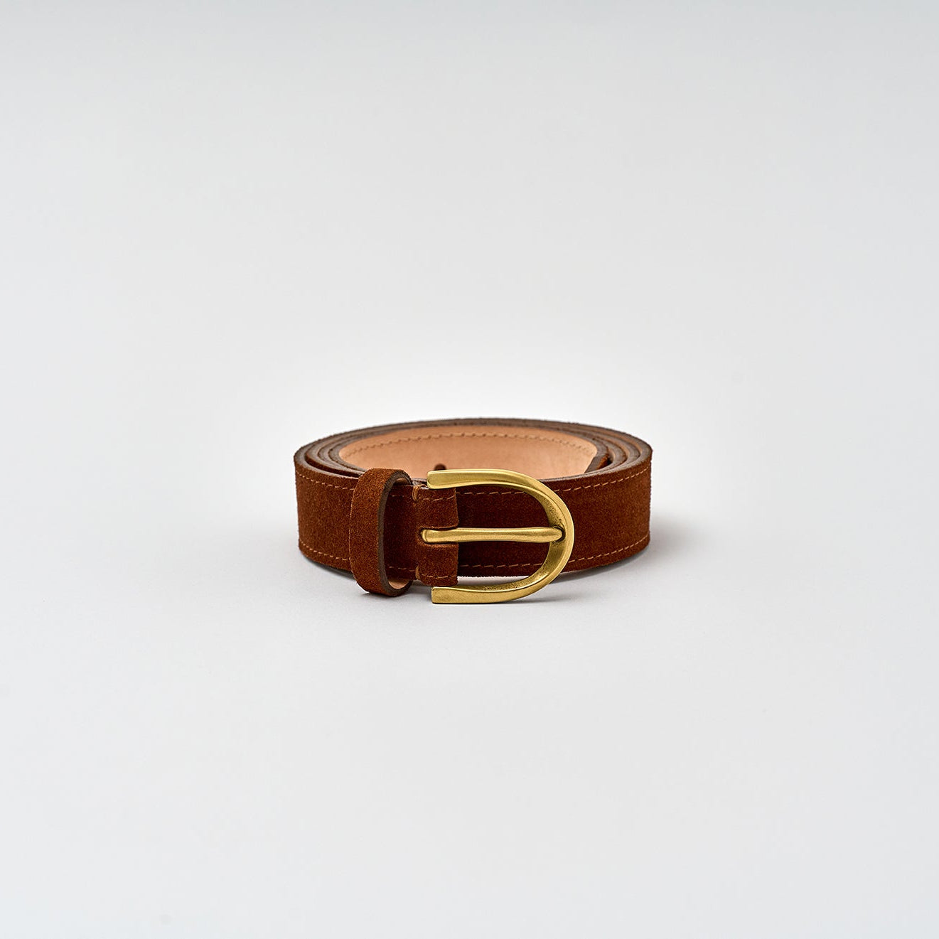 Brown leather belt with a gold buckle on a light gray background